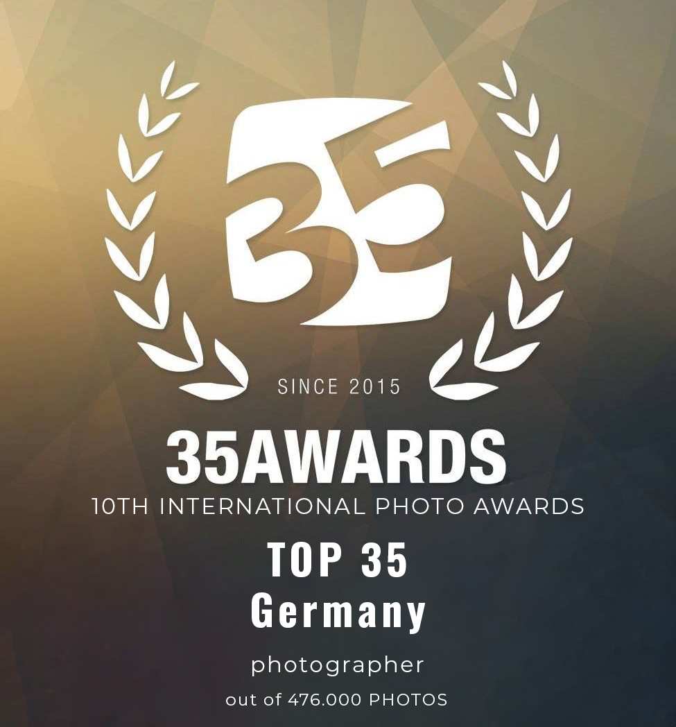 35AWARDS-Logo mit Lorbeerblättern, Text lautet: 10. International Photo Awards, TOP 35 Deutschland, Deutschlands beste Fotografen – Ballett, Tanz, Fotoshooting, Fotograf unter 476.000 Fotos, seit 2015. Dunkler geometrischer Hintergrund.